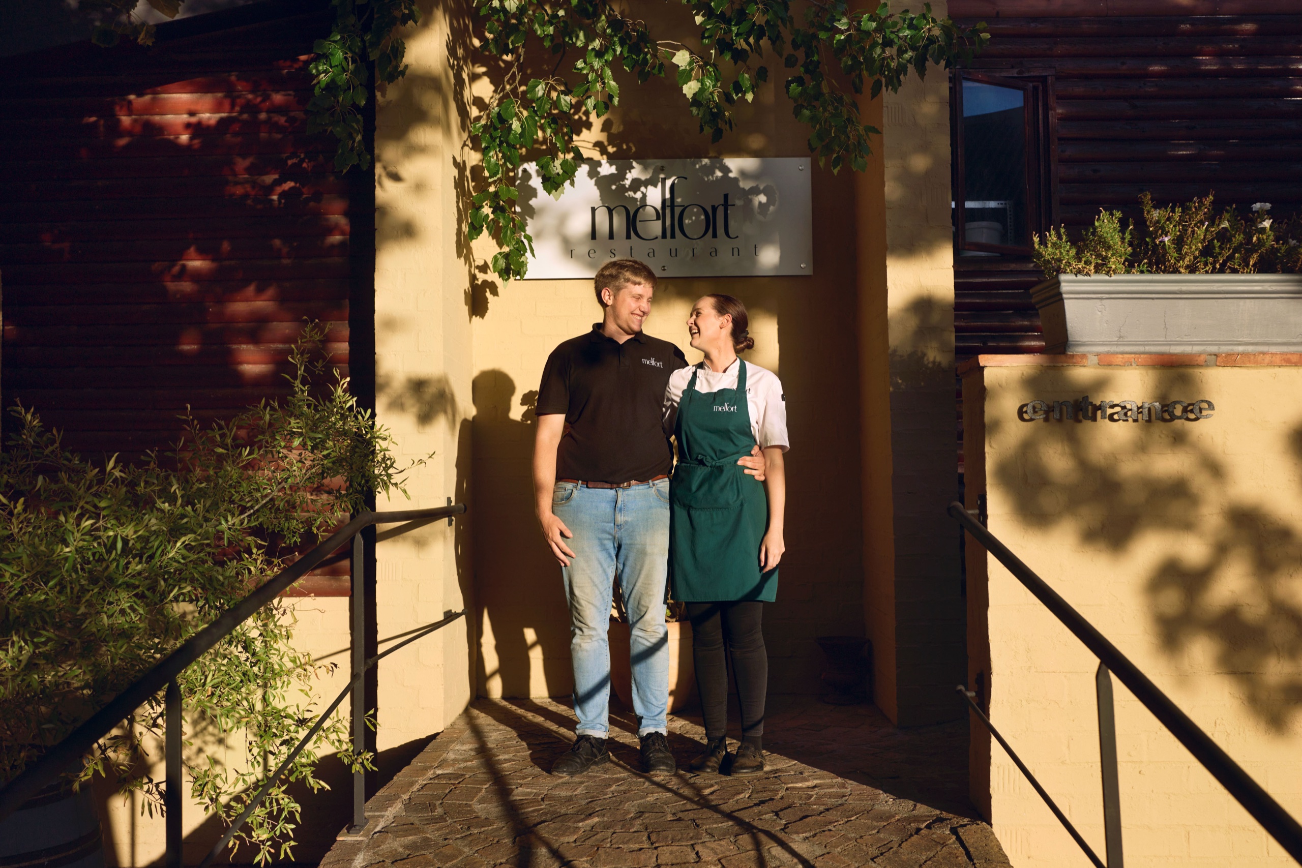 Two founders stand together at their restaurant entrance in golden evening light